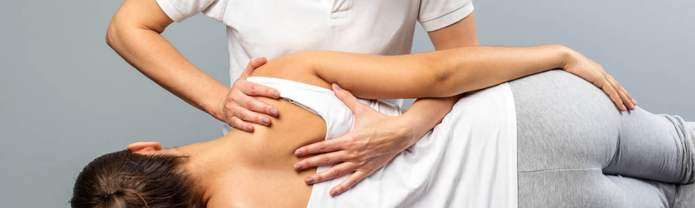 Close-up of female chiropractor doing a back adjustment on a female patient at a clinic